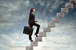 Mujer-con-un-maletin-subiendo-una-escalera-con-el-cielo-de-fondo